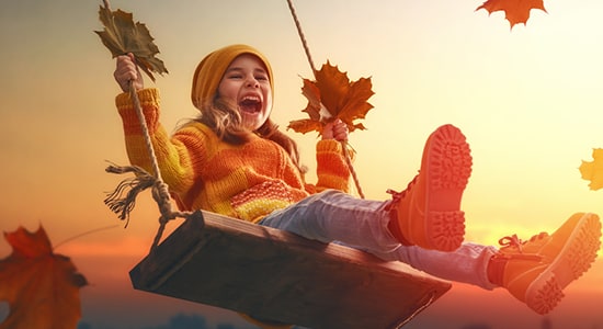 A girl swinging with an autumn landscape in the background