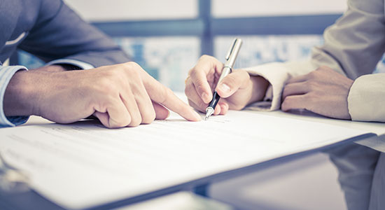 A hand pointing to a document to be signed